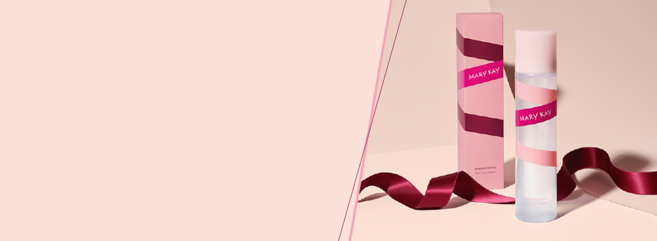 Das Mary Kay® Silkening Dry Oil steht neben seiner elegnaten pinken Verpackung vor einem hellrosanen Hintergrund. Dazwischen liegt ein gelocktes burgunderfarbenes Seidenband.