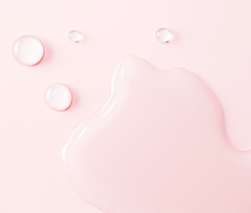 Auf einem rosafarbenen Hintergrund sieht man Tropfen einer Hautpflegecreme