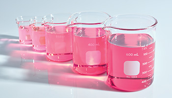 Fünf Reagenzgläser mit rosafarbener Flüssigkeit, die Feuchtigkeit spendet