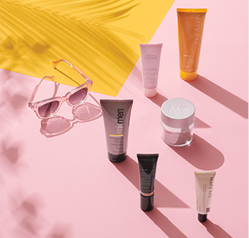 A picture of various Mary Kay skin care products and body care products with SPF sunscreen on a pink and yellow background with sunglasses