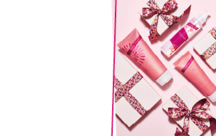 Perfekt für den Valentinstag: Mary Kay Mandarin Blooms Body Wash, Body Lotion und Duftspray liegen neben rosa verpackten Geschenken 