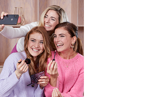 Bei einer Mary Kay Beauty Auszeit mit Freunden macht eine selbständige Schönheits-Consultant mit Mary Kay ein Selfie mit zwei Kundinnen, die gerade Mary Kay Lipgloss und Rouge auftragen.