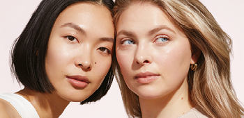 Nahaufnahme der Gesichter zweier junger Frauen (etwa 20 Jahre) mit unterschiedlichem Teint, Haut- und Haarfarbe - beide haben strahlende, reine Haut
