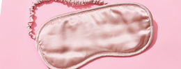 Seidige hellrosa Schlafmaske auf dunklerem rosa Hintergrund