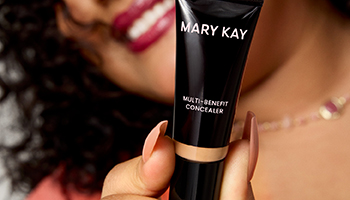 Eine Frau hält eine Tube Multi-Benefit Concealer von Mary Kay in die Kamera