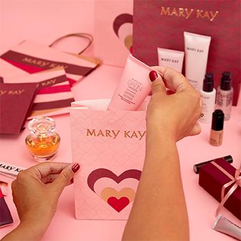 Auf einem rosafarbenen Tisch sind einige Geschenktütchen zu sehen, die gerade mit Mary Kay Produkte befüllt werden